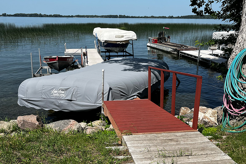 Covered boats on lift systems beside dock in West Central Minnesota.